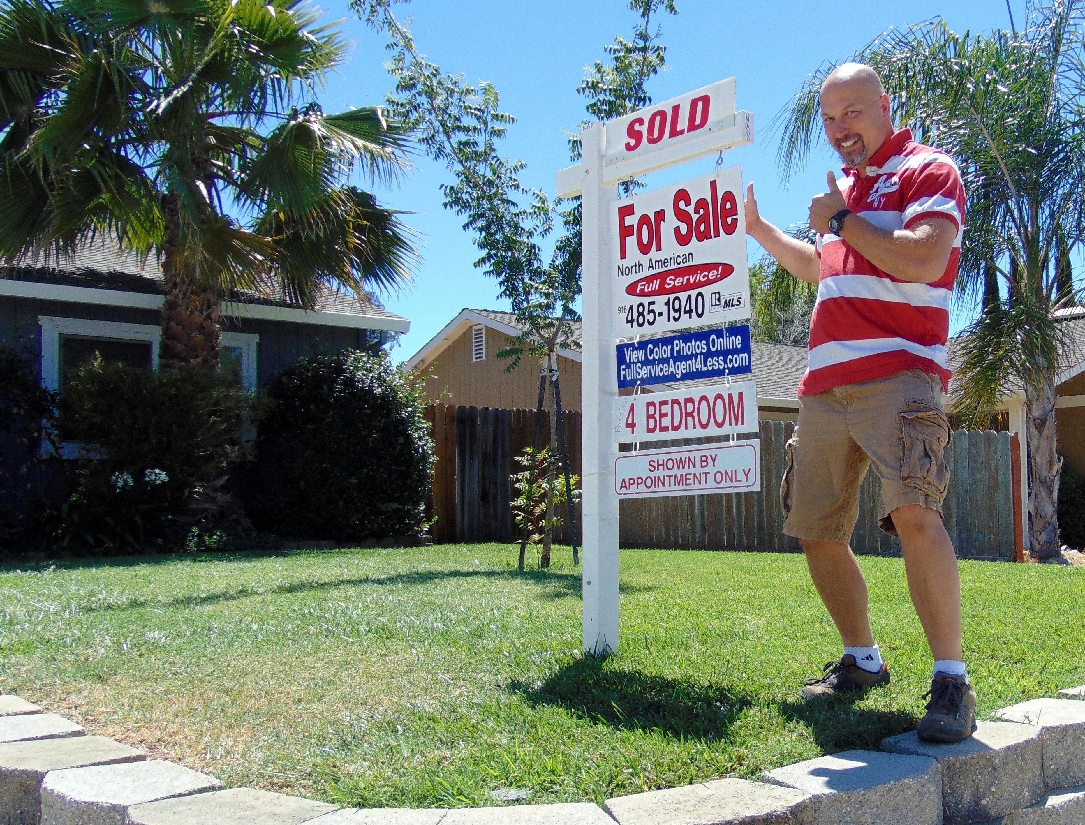 Seller standing outside his home next to our real estate for sale sign happy because the home is SOLD