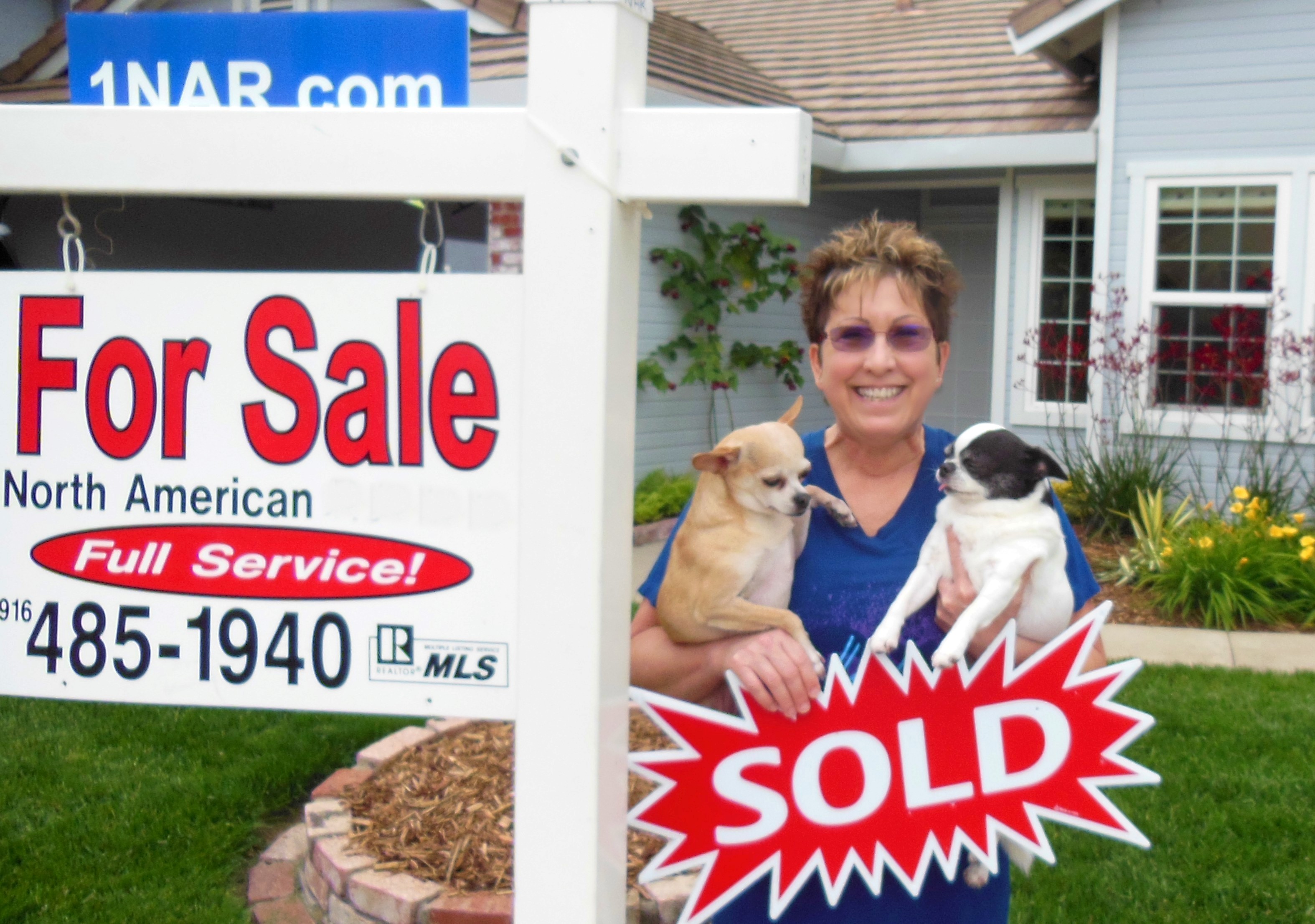 Seller standing outside her home next to our real estate for sale sign happy because the home is SOLD