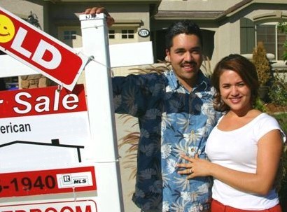 Sellers standing outside their home next to our real estate for sale sign happy because the home is SOLD